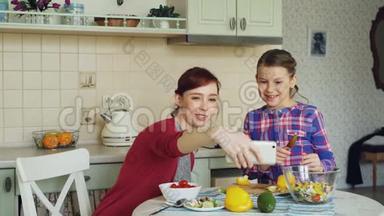 微笑的妈妈<strong>一起拍自拍</strong>照片，和年轻可爱的女儿<strong>一起</strong>在厨房家做早餐。 家庭，厨师